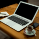 Bild von Arbeitsplatz mit Laptop, Handy, Notizheft und Kaffee